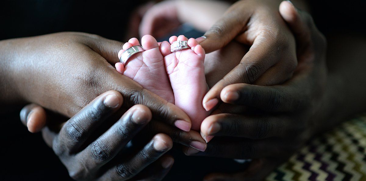 A Black couple holding their newborn baby