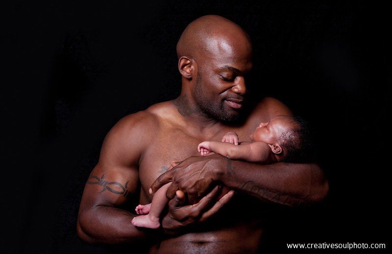 A tattooed father holding his child tenderly